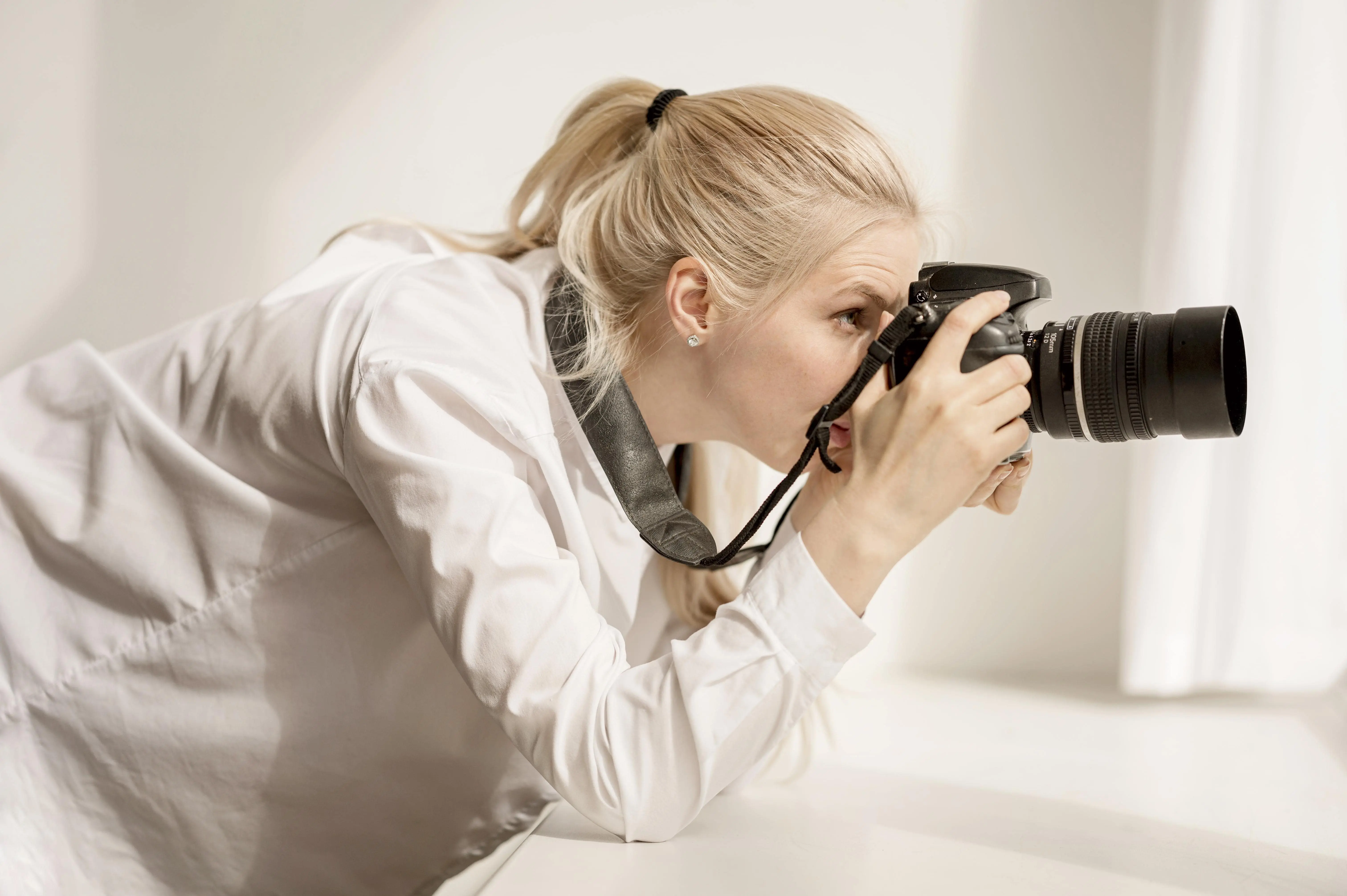 female-leaning-window-sill-taking-photo-min